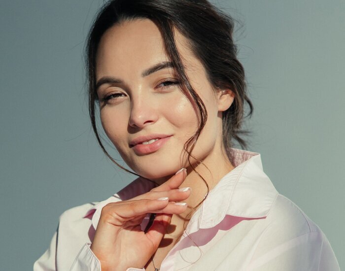 A woman dressed in a pink shirt poses for the camera, showcasing a bright and friendly demeanor.